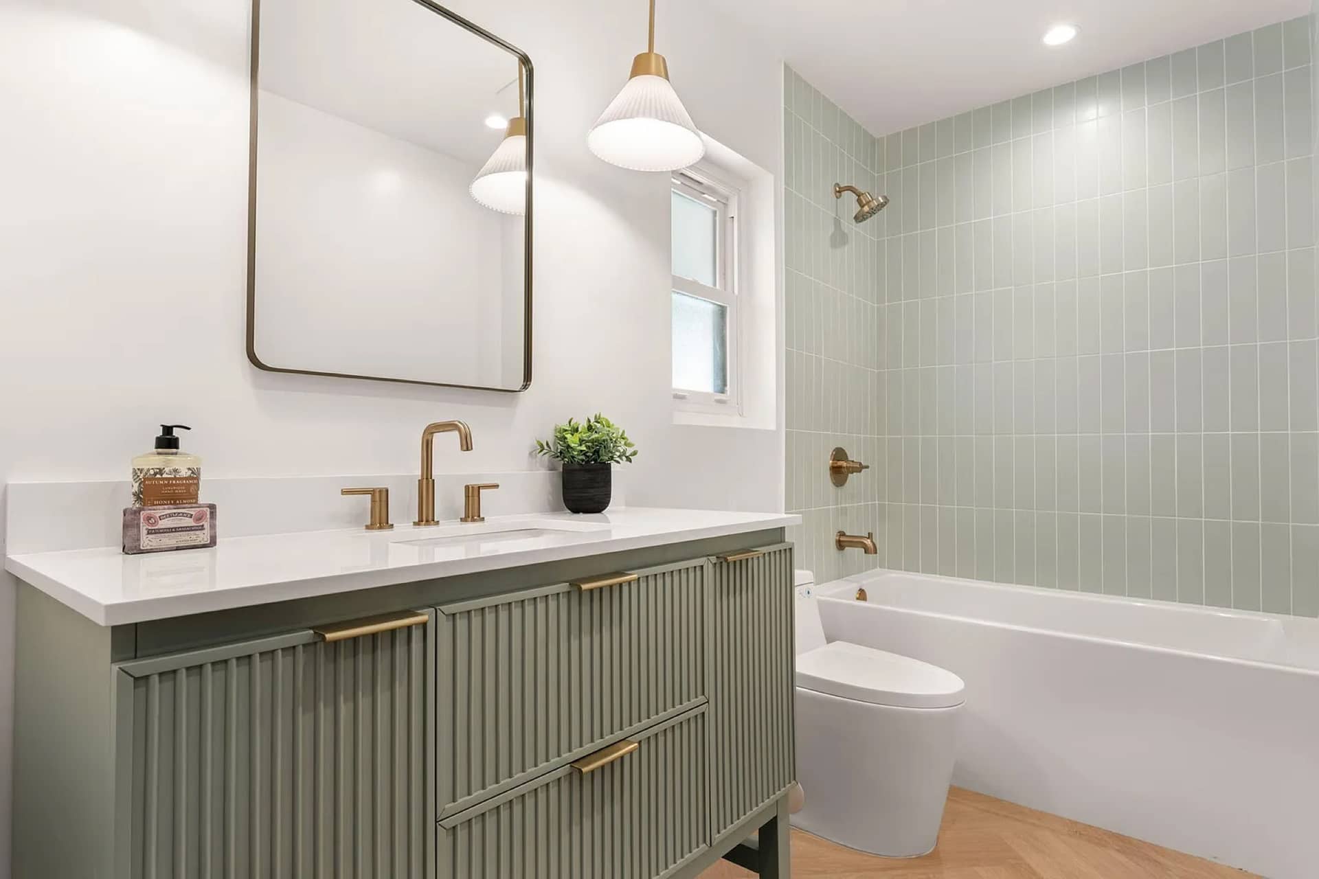 A Campanil bath: sage fluted vanity, brass fixtures, sage tile.