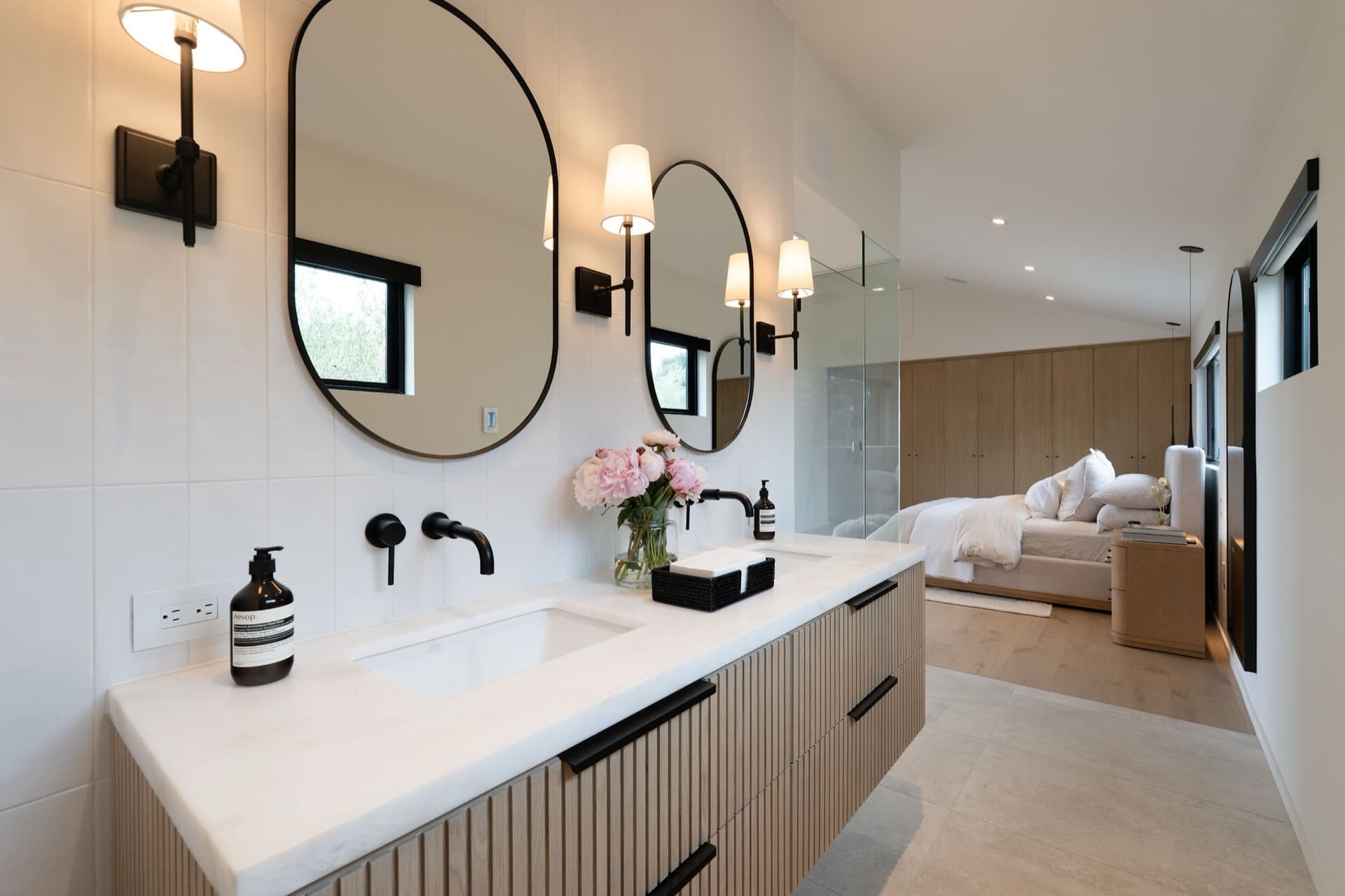 A bath vanity with a carved marble sink, fluted walnut cabinet and brass faucet.