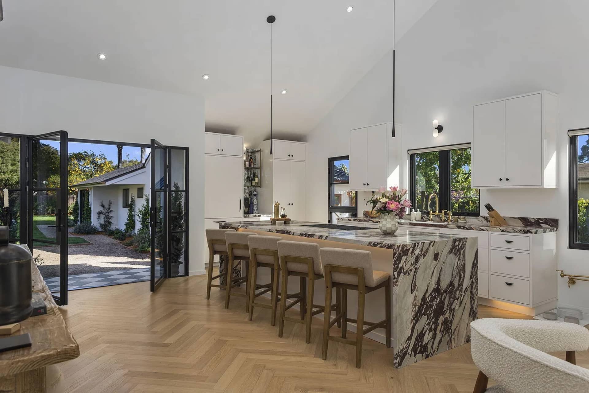 A San Roque kitchen: bookmatched marble island, steel doors to the courtyard.