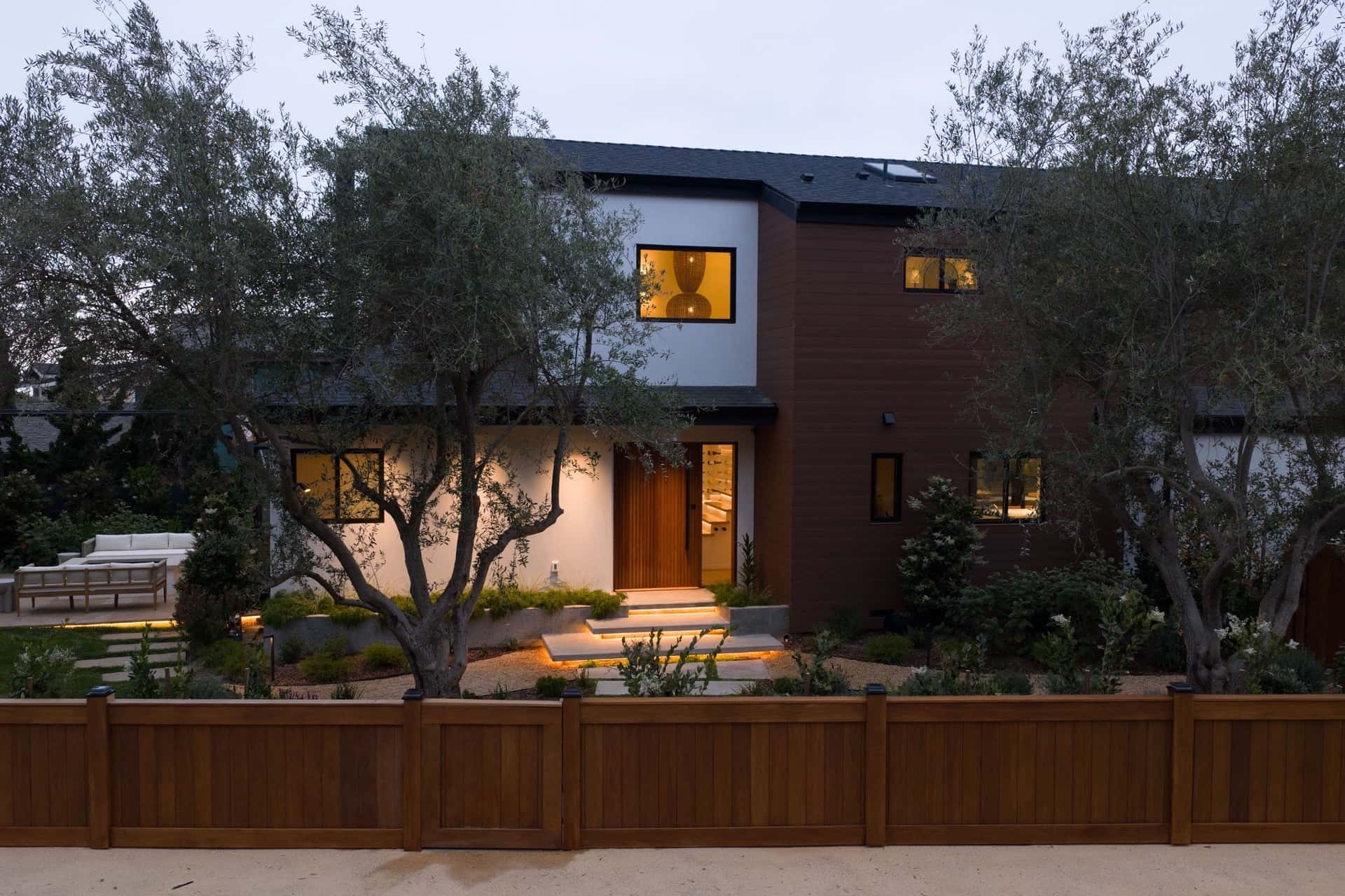 The Padaro Lane residence at dusk, seen through olive trees.