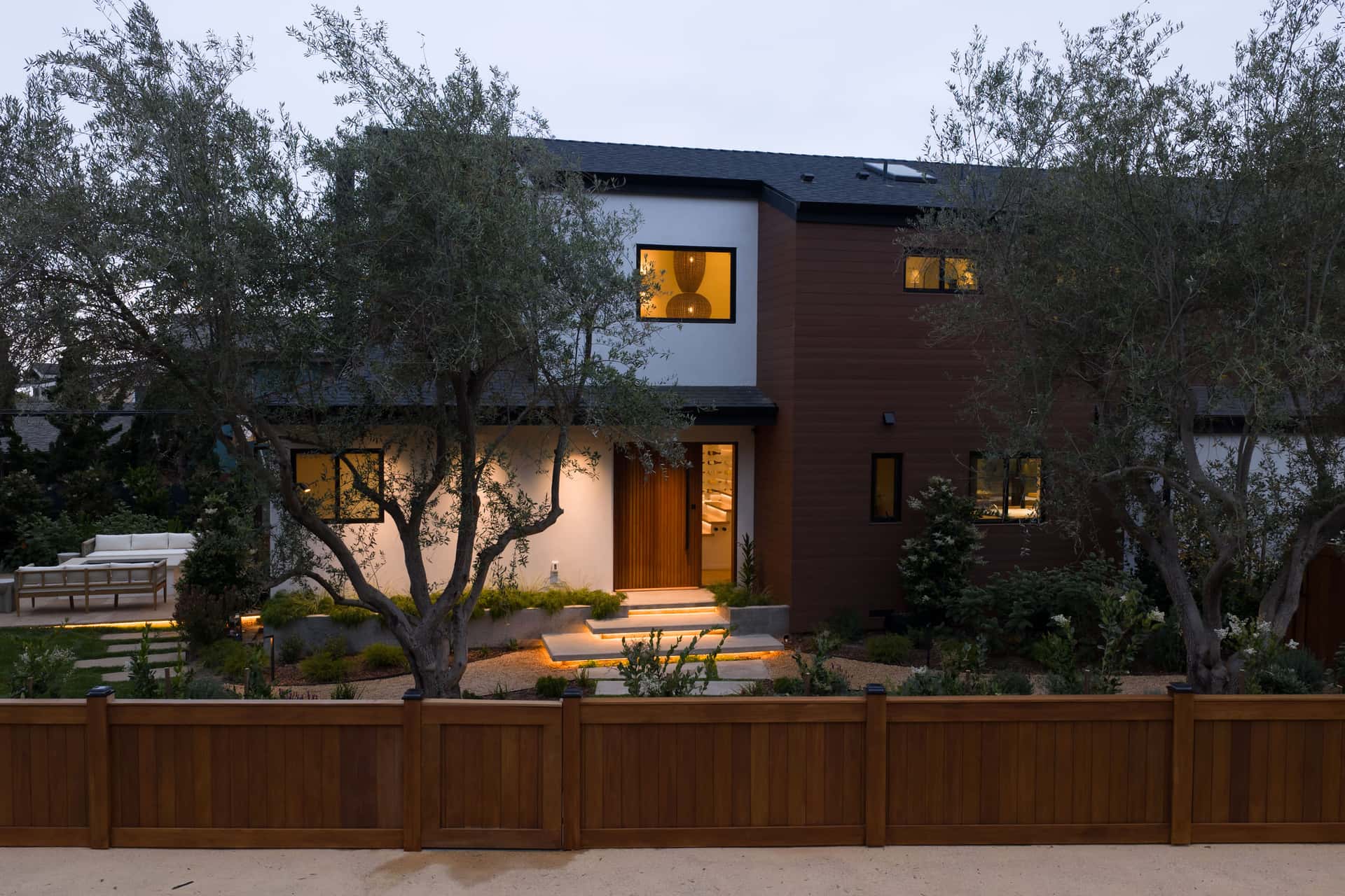 The Padaro Lane residence at dusk behind olive trees.